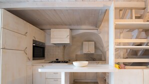 A kitchen with wooden cabinets, a white countertop, and a built-in oven. - Casa Daniele (Ostuni)