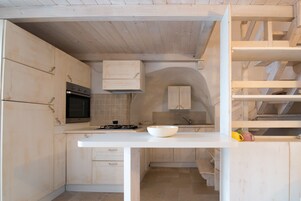 Una cocina con armarios de madera, encimera blanca y horno empotrado.
