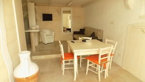 A dining area with a table and chairs, a white vase, and a staircase leading to another room. - Casa Daniele (Ostuni)