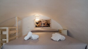 A cozy bedroom with a bed, two nightstands, a wooden shelf, and a wall-mounted picture. - Casa Daniele (Ostuni)