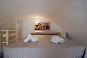 Een knus slaapkamer met een bed, twee nachtkastjes, een houten plank en een aan de muur hangend schilderij.