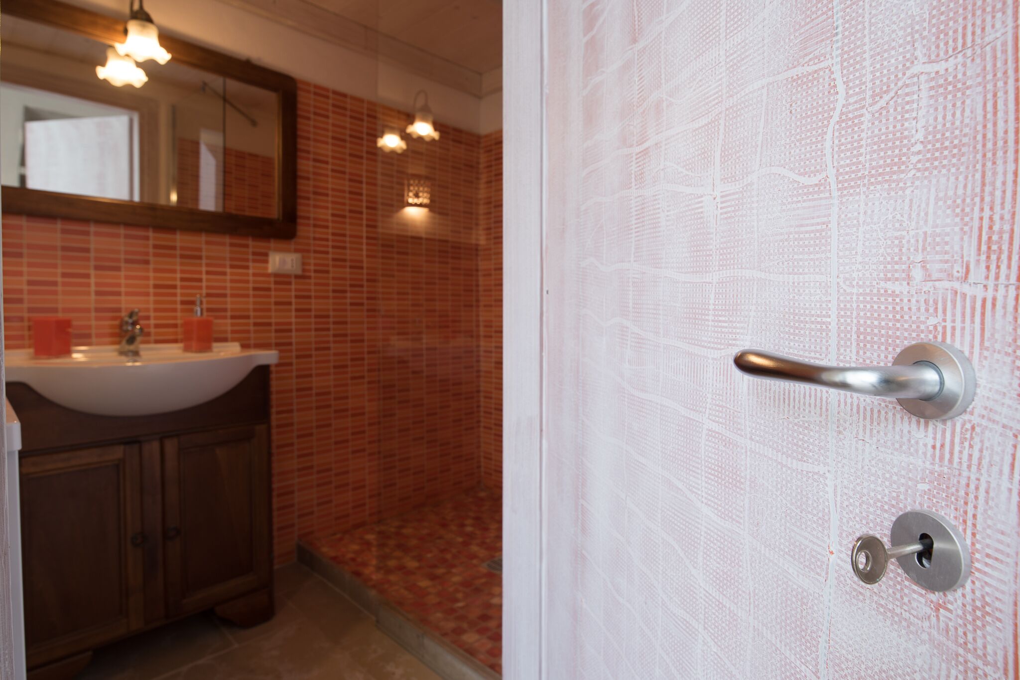 A bathroom with a sink, mirror, and tiled walls.
