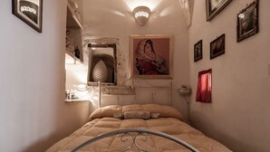 Ein Schlafzimmer mit einem Metallbettgestell, einer Wandregal mit Dekorationen und einem gerahmten Bild über dem Bett.