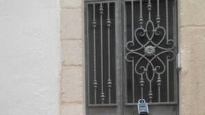 Ein Gebäude mit vergittertem Fenster und einem kleinen Vorhängeschloss.