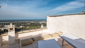 A balcony with a view of the city and sea, a table, and a bench. - Casina Nina (Ostuni)