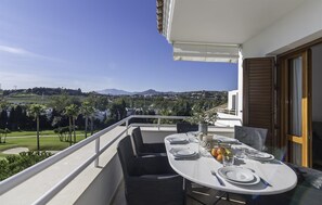 A balcony with a table set for dining, overlooking a scenic landscape with mountains and greenery. - Penthouse First Line Golf - Marbella (Marbella)