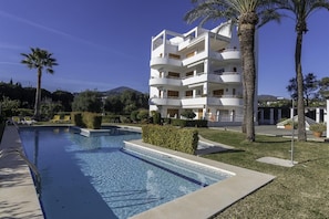 A modern hotel with a pool, surrounded by palm trees and a mountain in the background. - Penthouse First Line Golf - Marbella (Marbella)