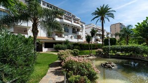 Un immeuble résidentiel doté d’une piscine, entouré d’une végétation luxuriante et de palmiers.