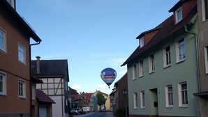 Una calle flanqueada por edificios, cielo despejado y un globo aerostático a lo lejos.