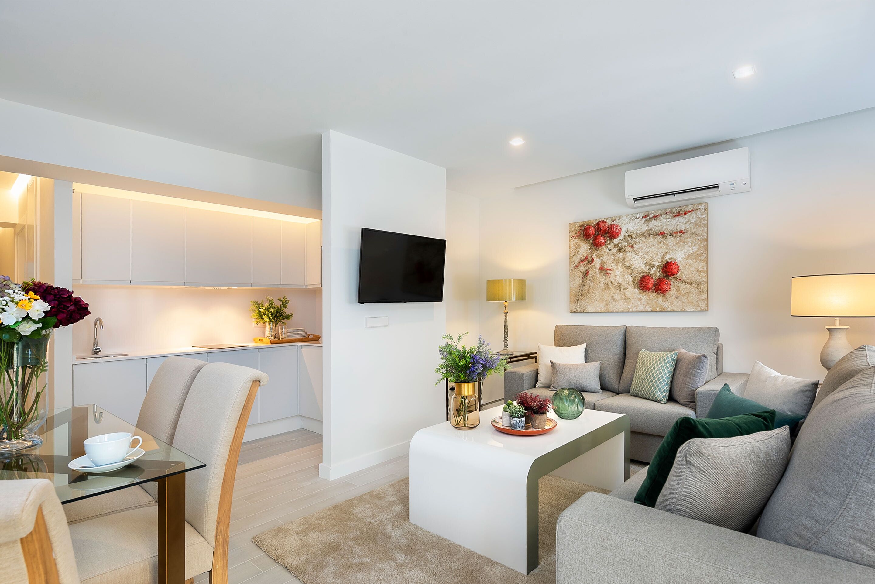 A modern living room with a sofa, a coffee table, and a TV mounted on the wall.