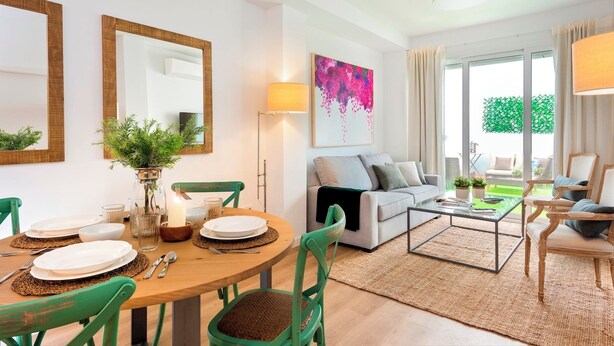 A modern living room with a dining area, a sofa, and a coffee table. There are two chairs, a lamp, and a painting on the wall. - Genteel Home Baños (Seville)