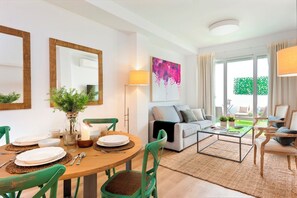 Un salon moderne comprenant un coin repas, un canapé et une table basse. On y trouve deux fauteuils, une lampe et un tableau accroché au mur.