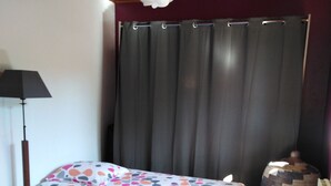 Een slaapkamer met twee bedden, een lamp, een gordijn en een decoratieve vaas.