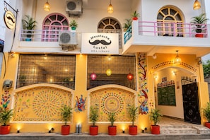 A hostel with a mustache logo, colorful murals, and potted plants.
