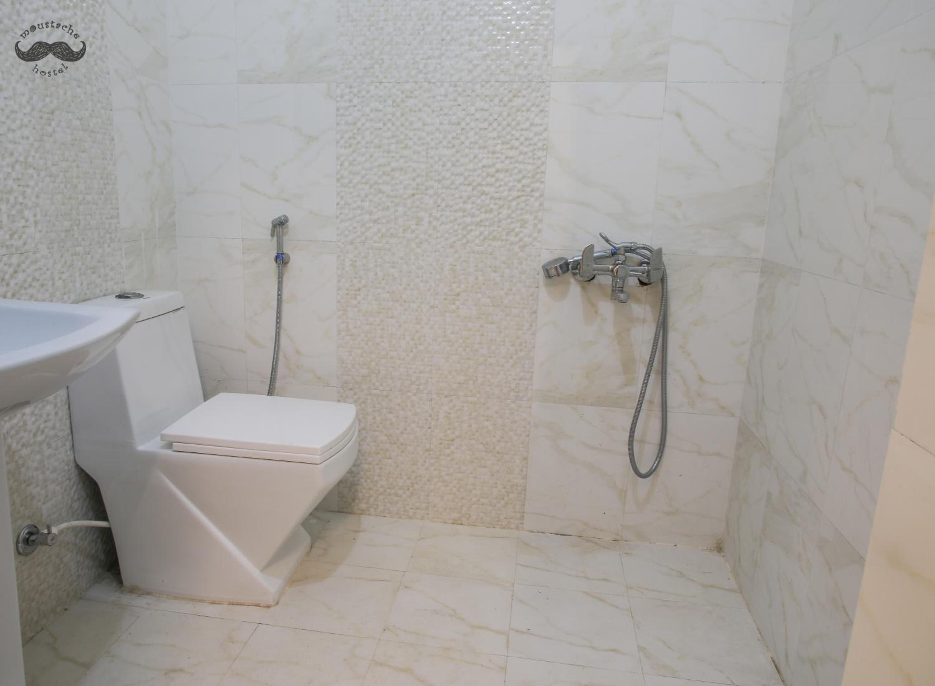 Un baño con inodoro, lavamanos y ducha con cabezal de ducha manual.