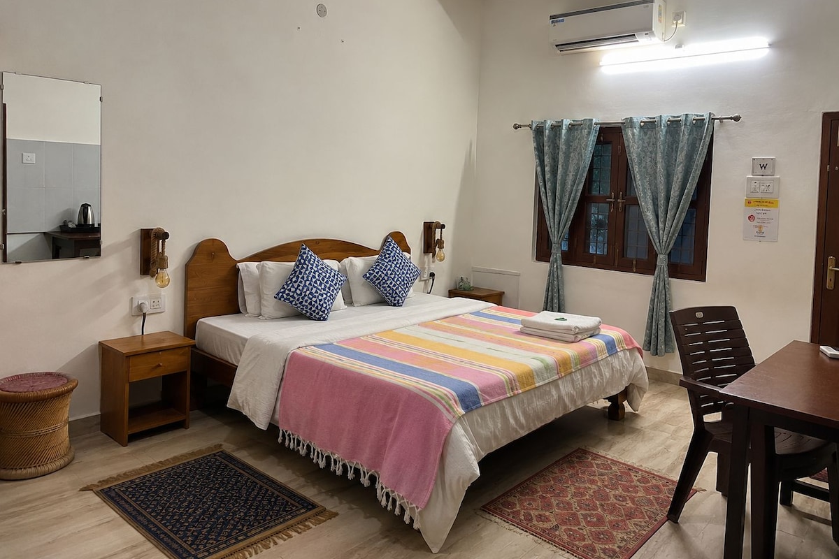A bedroom with a bed, bedside tables, a mirror, a window with curtains, a desk, and a chair.