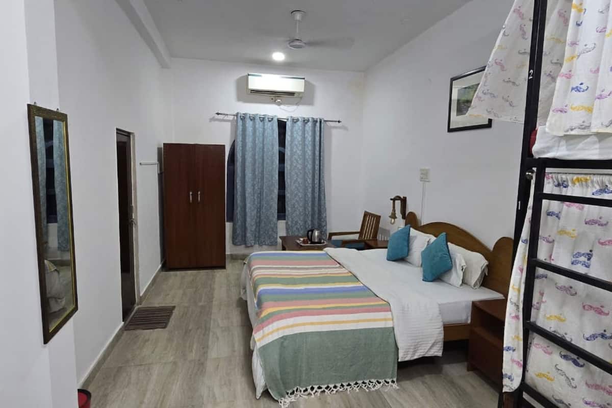 A bedroom with a bed, a wardrobe, a ceiling fan, and a window with curtains.