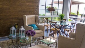 Un salon moderne comprenant un canapé, des fauteuils, une table basse en verre et une petite table d’appoint agrémentée d’objets décoratifs.