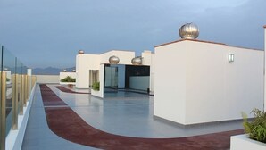 Une terrasse sur le toit dotée d’un chemin rouge incurvé, de murs blancs et d’éléments décoratifs sphériques.