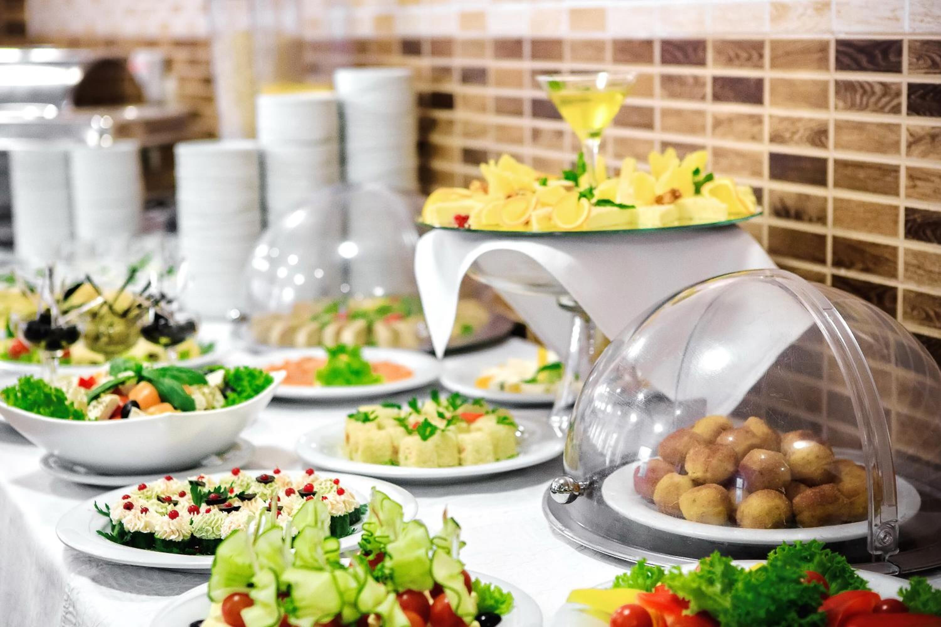 A buffet table with various dishes, including salads, appetizers, and covered items.