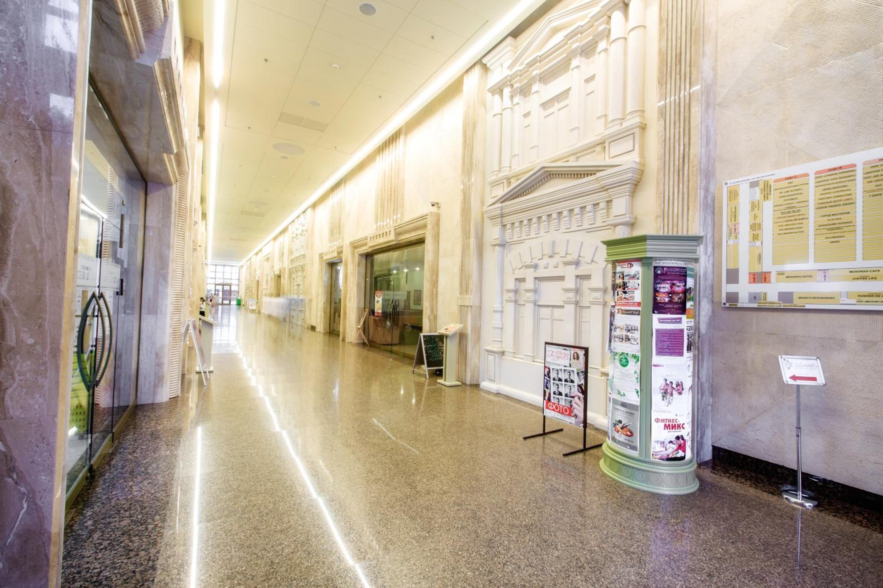 A long, polished corridor with marble walls and columns, leading to a grand entrance.
