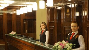 A hotel reception area with wooden paneling, a reception desk, and a large mirror. - 7 Days City Hotel (Dnipro)