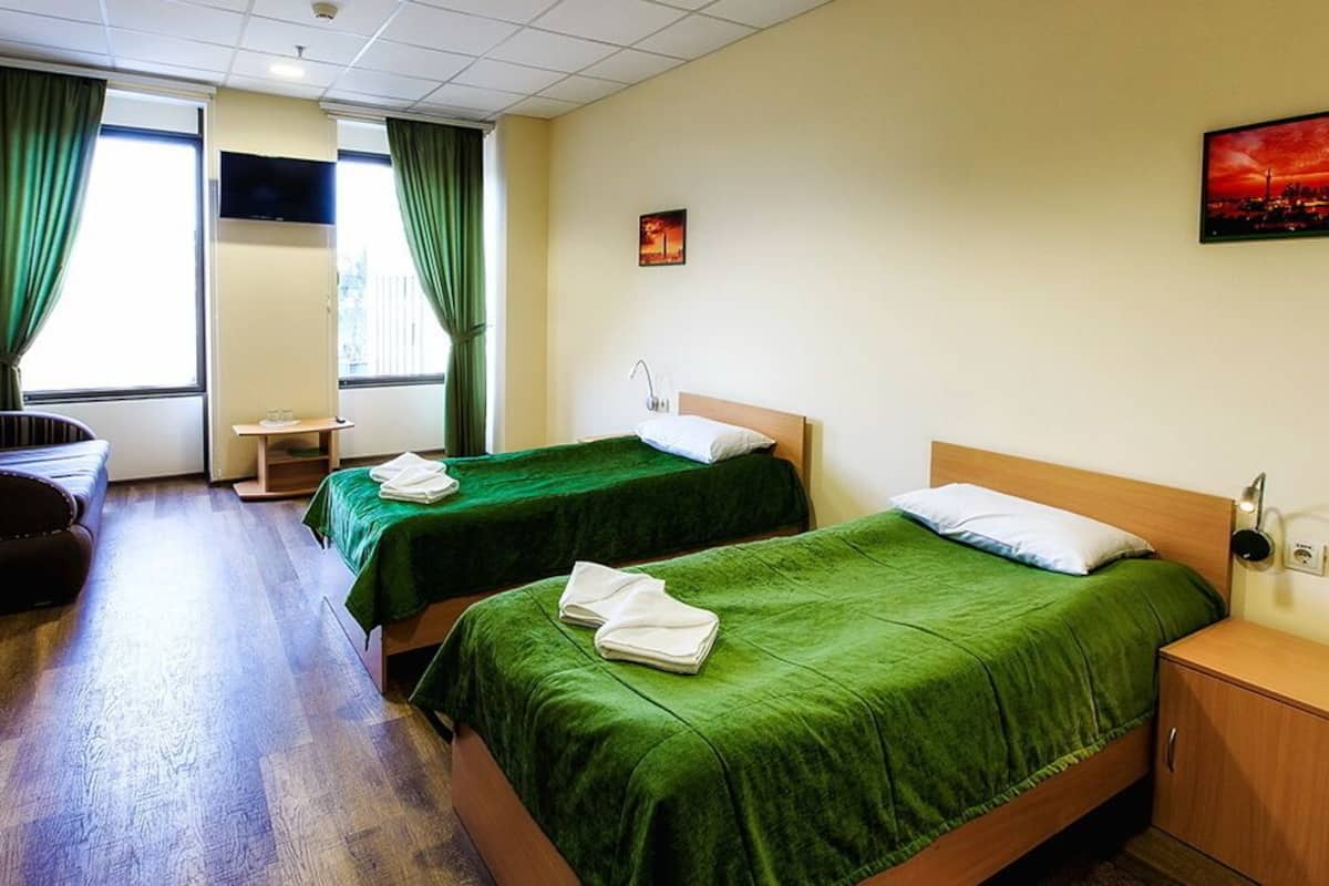 A hotel room with two beds, a sofa, a TV, and a painting on the wall.
