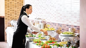 A buffet setup with various food items and a person serving. - 7 Days City Hotel (Dnipro)
