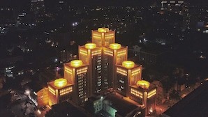 A high-rise building with multiple illuminated floors, surrounded by other buildings. - 7 Days City Hotel (Dnipro)