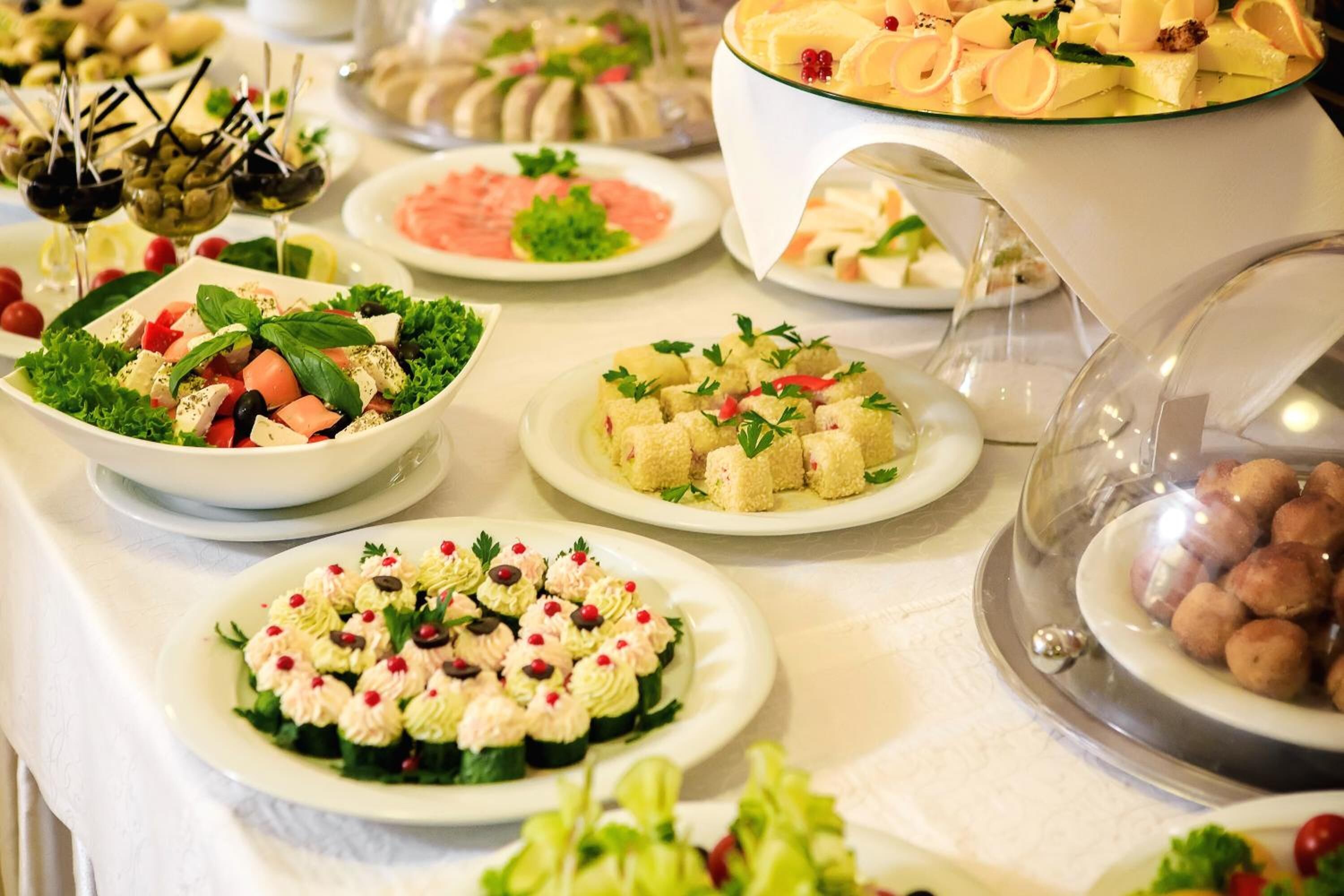 A buffet with various dishes including salads, cheeses, and other appetizers.