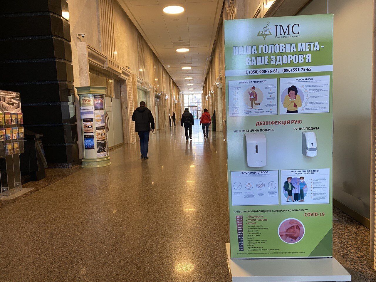 Un pasillo con carteles informativos, un directorio y una zona de recepción.