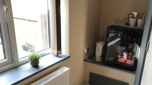 Eine kleine Küche mit einem eingebauten Kühlschrank, einem Fenster mit einer Pflanze und einer Heizung.