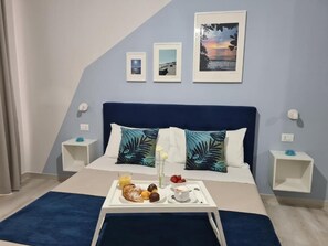 Una habitación de hotel moderna con una cama, una bandeja de desayuno y tres cuadros en la pared.