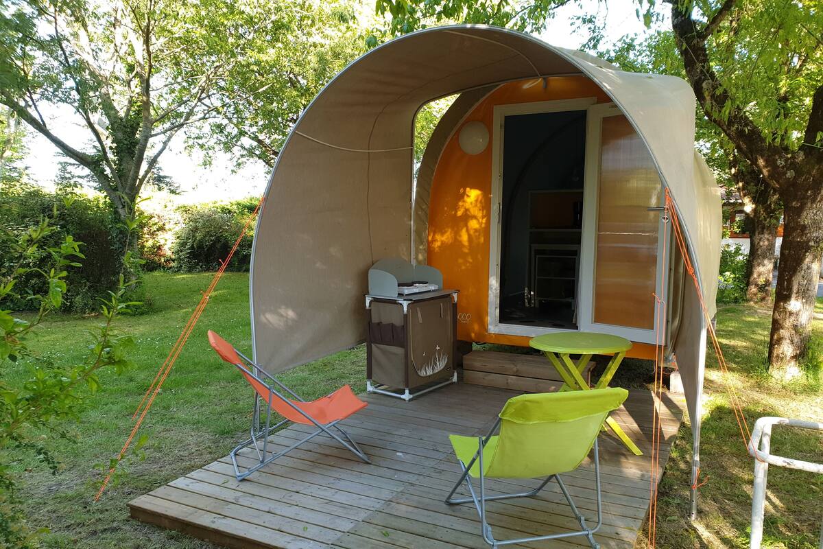 Une petite structure extérieure fermée, dotée d’une terrasse, d’un barbecue et de deux chaises.