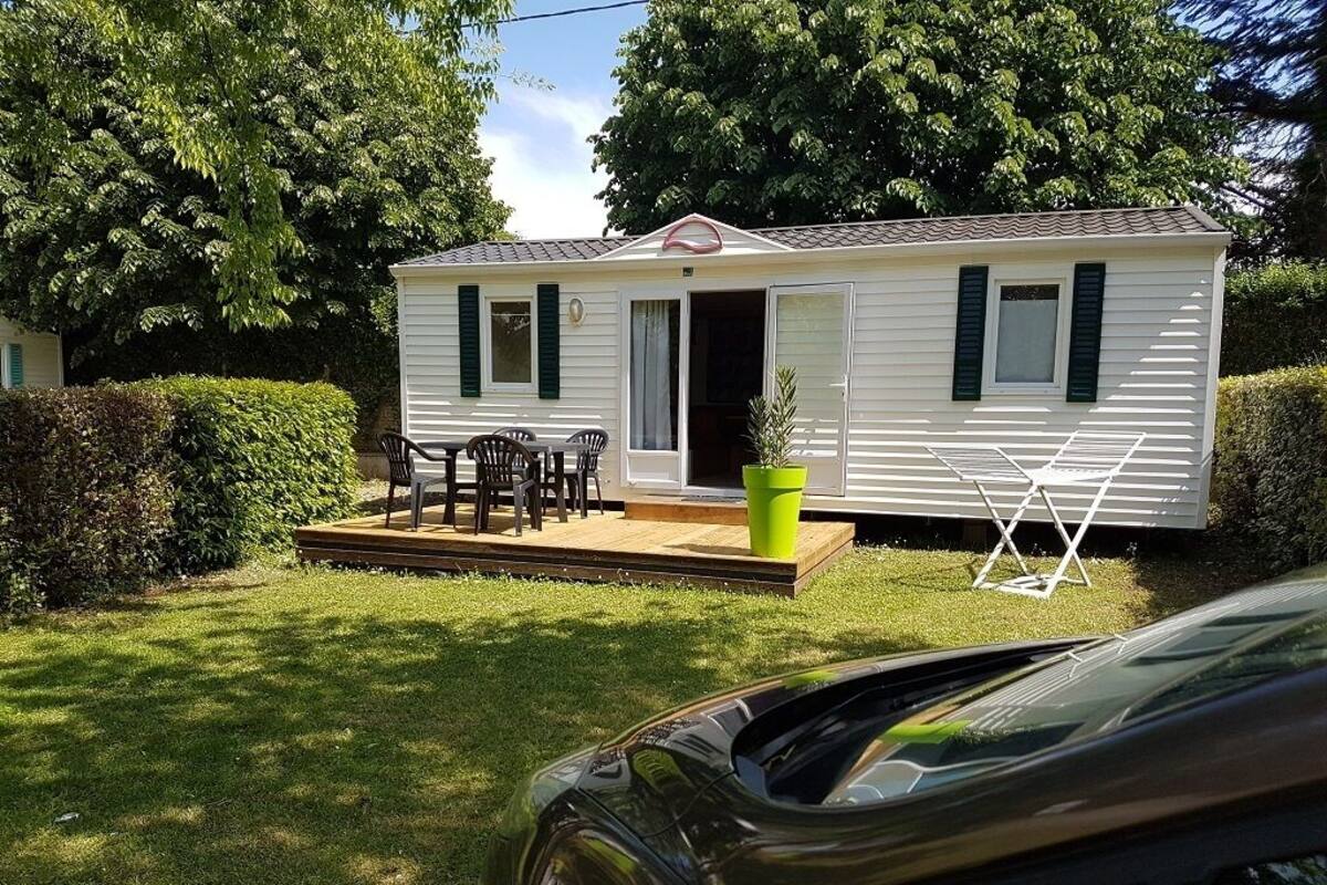 Une maison mobile dotée d’un patio, d’un jardinière et d’un étendoir à linge.