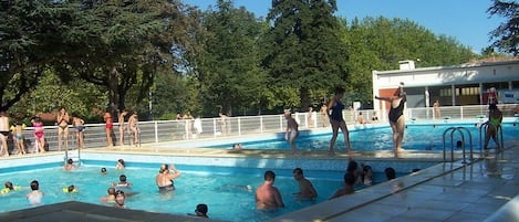 Una piscina al aire libre de temporada, sombrillas