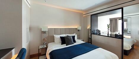 A modern hotel room with a large bed, a desk, and a mirror.