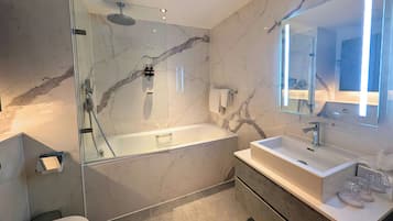 Une salle de bain moderne avec une douche à parois de verre, une baignoire sur pied et un meuble-lavabo avec un miroir.
