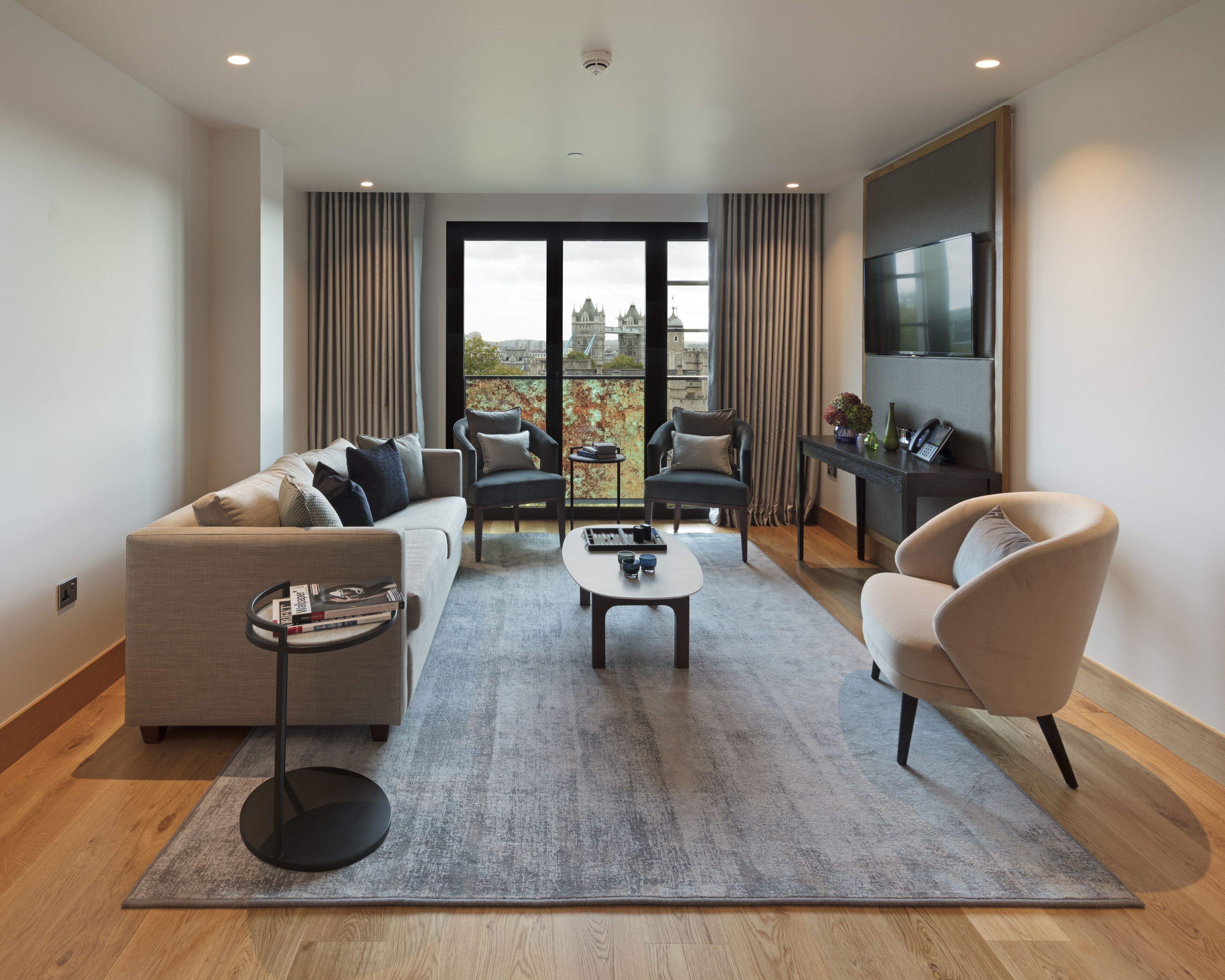 A modern living room with a sofa, armchairs, a coffee table, and a TV.