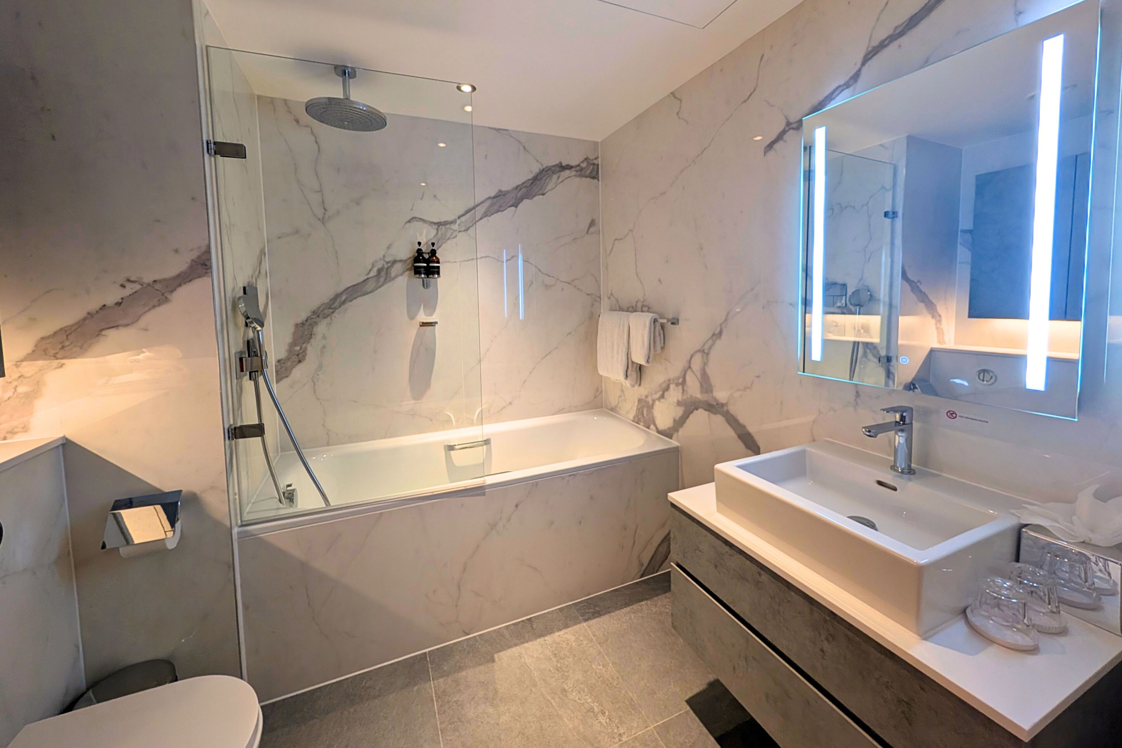 Une salle de bain moderne dotée d’une douche à parois de verre, d’une baignoire sur pieds et d’un meuble-lavabo avec un miroir.