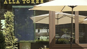 An outdoor seating area with yellow chairs and a table, a menu board, and a sign reading "CENTO ALLA TORRE". - Tower Suites by Blue Orchid (London)