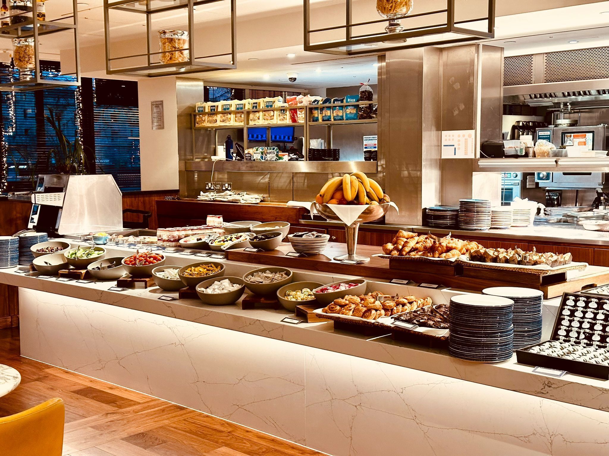 A buffet with various food items and a kitchen area in the background.