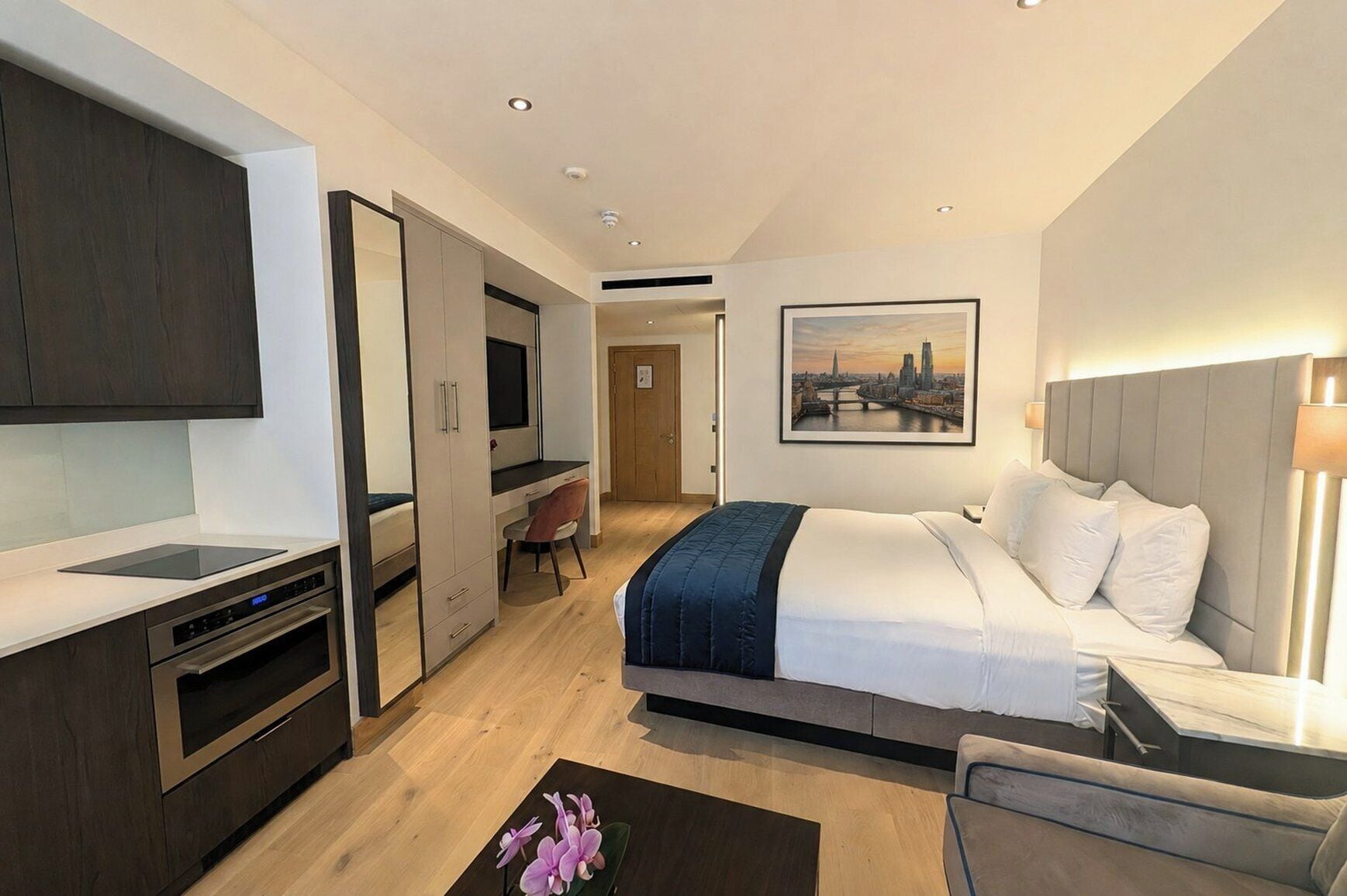 Una habitación de hotel moderna con cama, escritorio y kitchenette.