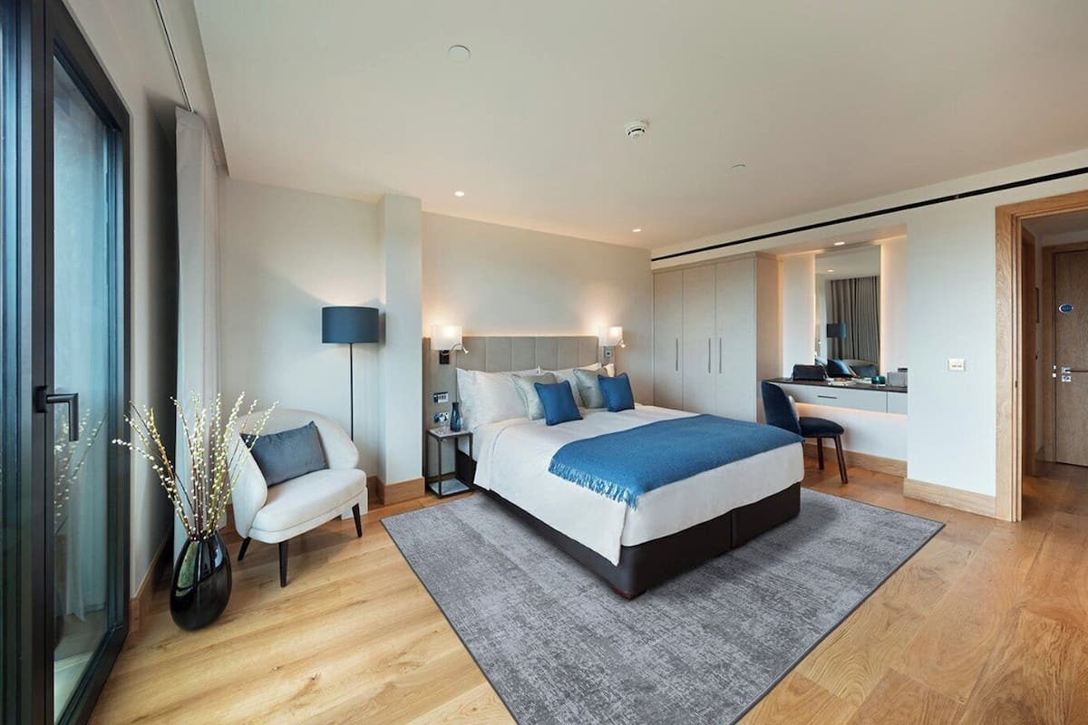 A modern bedroom with a large bed, bedside tables, a desk, and a chair.