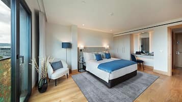 A modern bedroom with a large bed, bedside tables, a desk, and a chair.