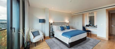 A modern bedroom with a large bed, bedside tables, a desk, and a chair.