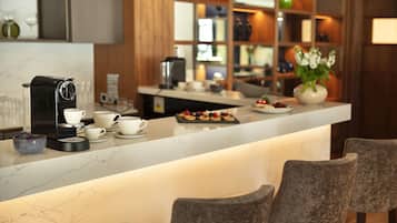 Eine moderne Küche mit Marmorarbeitsplatte, einer Kaffeemaschine und einer Bar mit Sitzgelegenheiten.