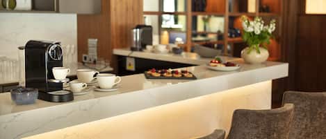 Una cocina moderna con encimera de mármol, cafetera y zona de bar con asientos.