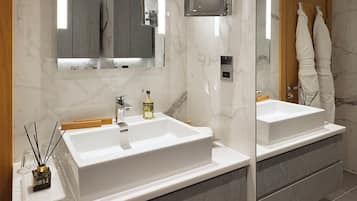 A modern bathroom with two white sinks, a mirror, and a wooden door.