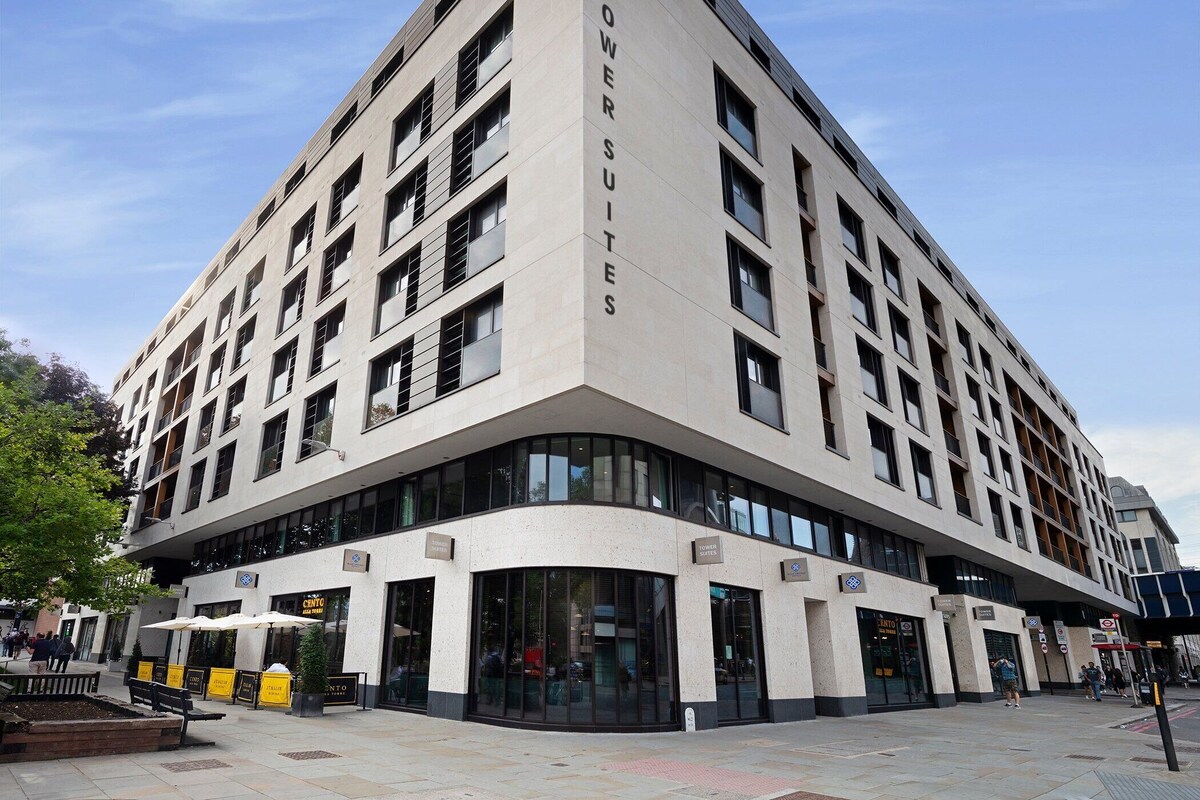 A modern hotel with a corner entrance, multiple floors, and a prominent 'Tower Suites' sign.